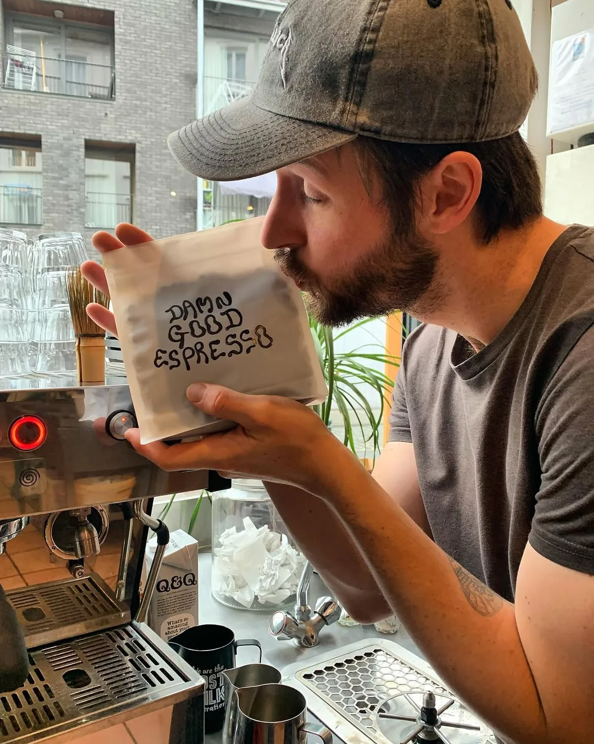Un barista sent un sachet de café marqué Damn Good Espresso au feutre noir