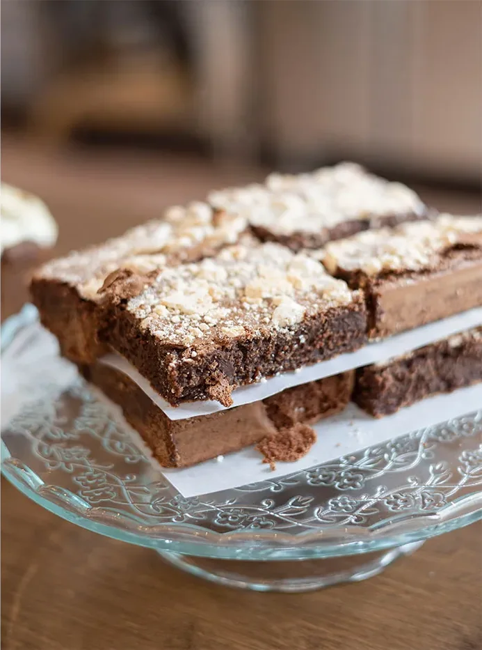 Chocolate brownies stacked on a cut-glass cake stand