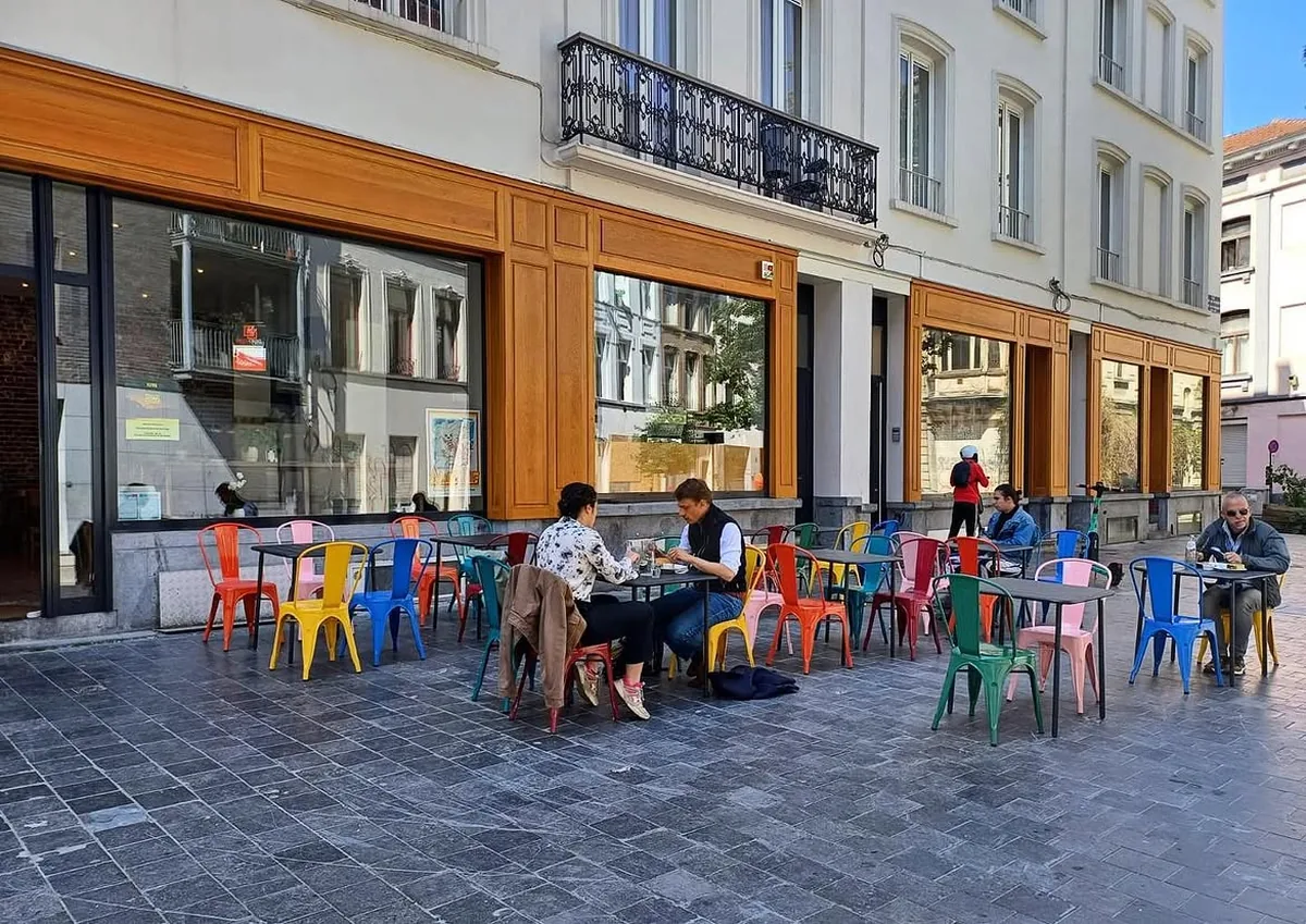 La terrasse du café et ses chaises Tolix rouges, jaunes, bleues et roses sur les pavés